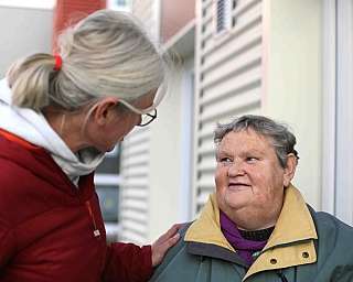 Eine ältere Frau spricht mit einer jüngeren Frau draußen.