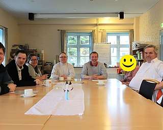 Gruppe von Personen an einem Tisch bei einer Besprechung.