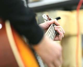 Nahaufnahme einer Hand, die auf den Saiten einer Akustikgitarre spielt