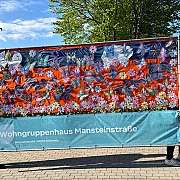Banner mit bunten Schmetterlingen und Blumen, gehalten von zwei Personen draußen